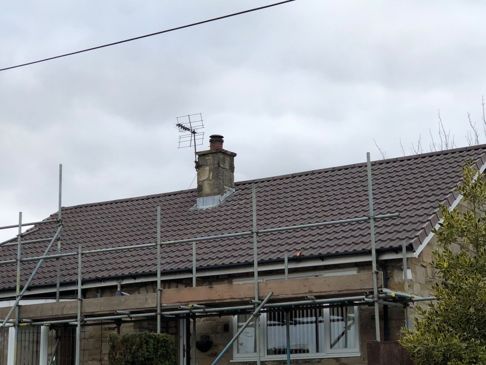 Bungalow re-roof in progress behind scaffold